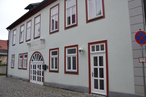 a white building with windows and doors on a street at Pension Thüringer Hof Hildburghausen in Hildburghausen