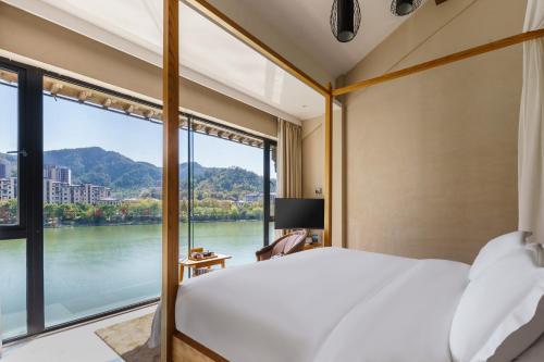 a bedroom with a bed and a view of a river at Huangshan Shanshuijian Wei Boutique Hotel in Huangshan