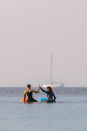 two people in the water with a sailboat in the ocean at Rødvig Kro og Badehotel in Rødvig