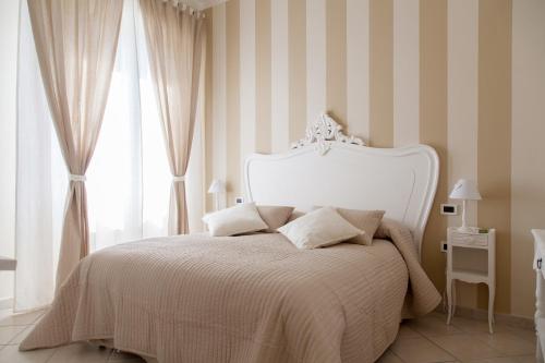 a bedroom with a white bed with striped walls at La Maison Des Anges in La Spezia