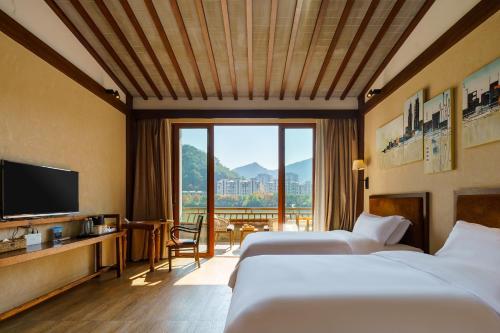a hotel room with two beds and a television at Huangshan Shanshuijian Wei Boutique Hotel in Huangshan