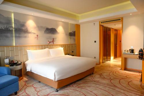 a bedroom with a large white bed and a blue couch at Pullman Wenzhou in Wenzhou