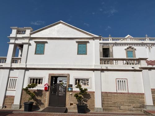 a white house with a black door in front at 八八金歐王金城洋樓古厝民宿 in Jinsha