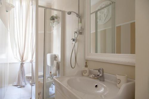 a white bathroom with a sink and a shower at La Maison Des Anges in La Spezia