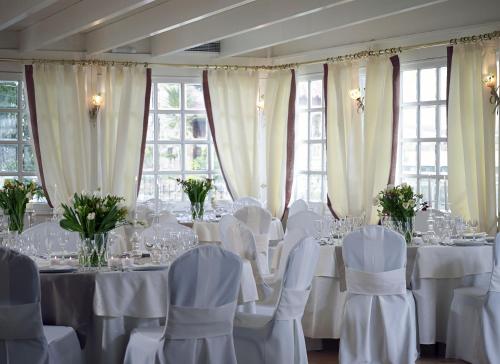a dining room with white tables and chairs and windows at Amarilia Hotel in Athens