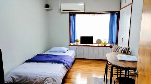 two beds in a room with a table and a window at Kokusaigakusya Ozukikaikan - Vacation STAY 17326 in Hadano