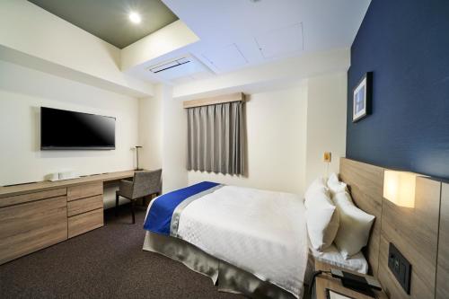 a hotel room with a bed and a desk and a tv at Best Western Plus Hotel Fino Osaka Kitahama in Osaka