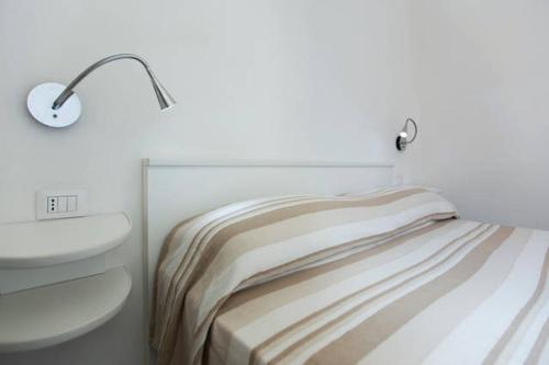 a white bedroom with a bed and a lamp at Holiday home Isola Rossa in Isola Rossa