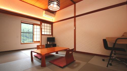 a room with a desk and a table and chairs at Ryokan Maruya in Yufuin
