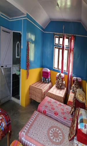 a room with three beds in a room with blue walls at Yangzon Homestay By StayApart in Simāna Basti