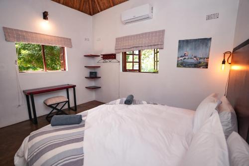 a bedroom with a bed and a desk and two windows at The Little Outlook in Victoria Falls