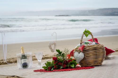 a picnic table with a basket and wine glasses on the beach at African Oceans Manor on the Beach in Mossel Bay