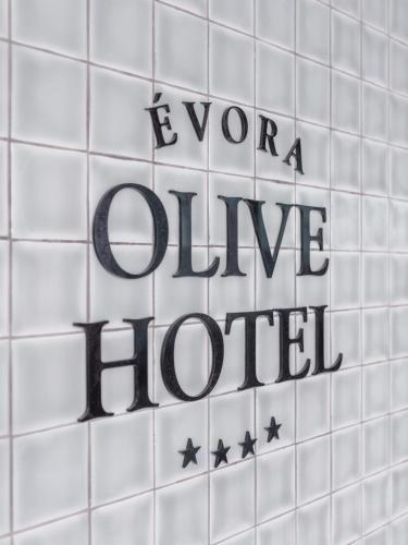 a sign on a white tiled wall with the words pour divine liquid at Evora Olive Hotel in Évora