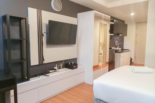 a bedroom with a television and a white bed at Cozy Studio at Mataram City Apartment By Travelio in Kejayan