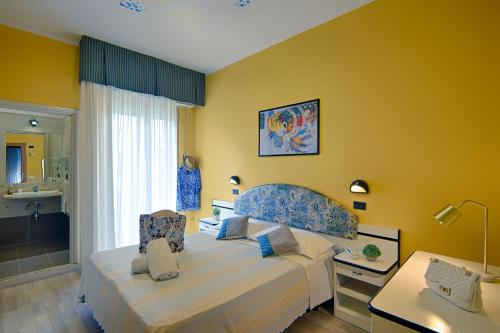 a bedroom with a large bed and a yellow wall at Hotel Madison in Bellaria-Igea Marina