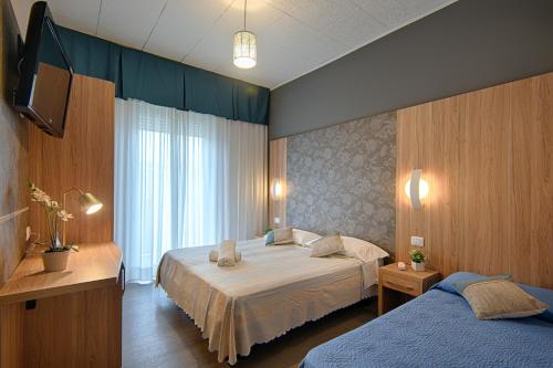 a bedroom with two beds and a television in it at Hotel Madison in Bellaria-Igea Marina