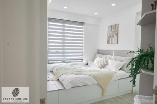 a white bedroom with a bed and a window at Sarene Lumiere Riverside Thao Dien in Ho Chi Minh City