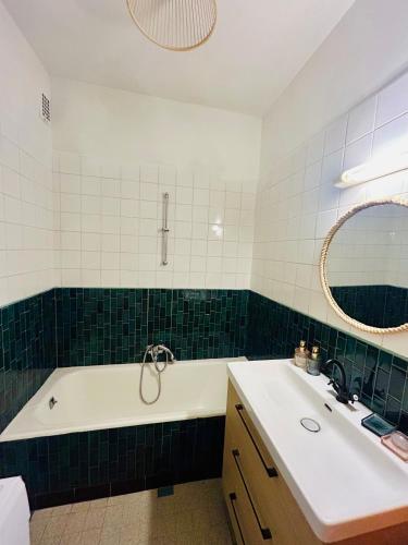 une salle de bain avec une baignoire, un lavabo et un miroir dans l'établissement Charmant rez-de-jardin lumineux en plein centre ville de Grenoble, à Grenoble