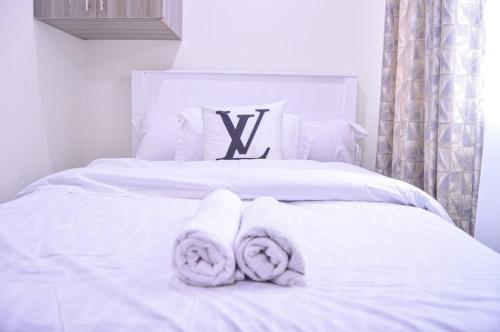 a white bed with towels on top of it at Lux Suites L&N Apartments Utawala in Embakasi