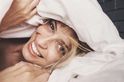 a woman laying in bed with her head at TauberChalet I Privates Boutique-Ferienhaus mit Whirlpool, Sauna, Garten, Naturmagie & ZellBoost in Rothenburg ob der Tauber