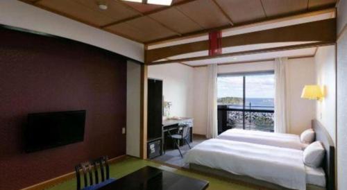 a bedroom with a bed and a desk and a television at Hotel Saiyou WAKIGAWA in Hirado