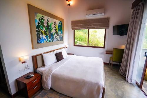 a bedroom with a white bed and a window at Hanthana Eco Lodge in Kandy