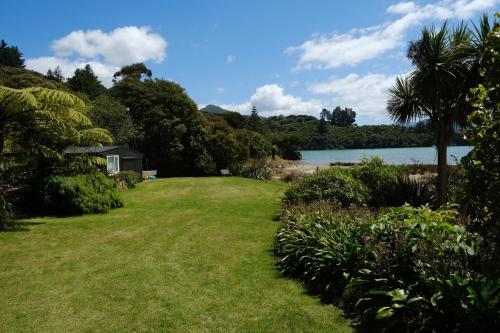 a grassy yard with a lake in the background at Luxury Waterfront Retreat at Mahau Sound in Ohingaroa