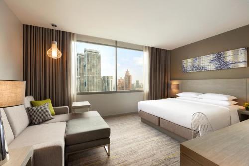a hotel room with a bed and a couch at Hyatt Place Bangkok Sukhumvit 24 in Bangkok