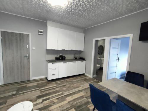 a kitchen with white cabinets and a table and blue chairs at 722 Slate Apartament Jedlina-Zdrój in Jedlina-Zdrój
