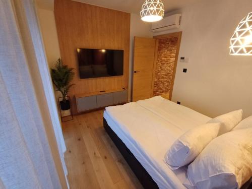 a bedroom with a white bed and a flat screen tv at Otyńska Point Apartamenty Prestige in Wrocław