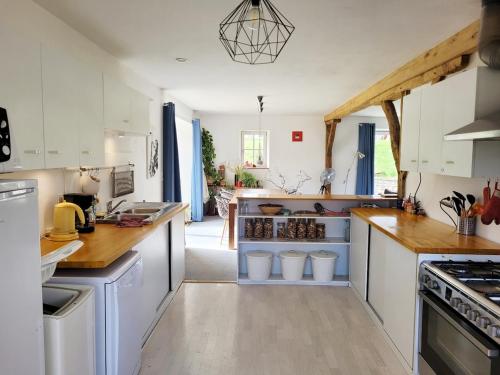 une cuisine avec des armoires blanches et des comptoirs en bois dans l'établissement Cottage familial, grand jardin, toboggan, barbecue, à Beurizot