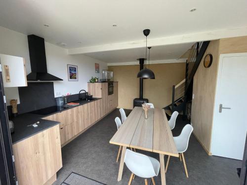 a kitchen with a wooden table and white chairs at Grange Plouer centre entre St Malo et Dinan in Plouër-sur-Rance