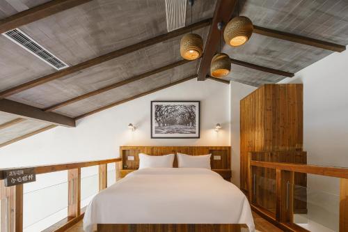a bedroom with a large white bed with wooden ceilings at Huangshan Shanshuijian Wei Boutique Hotel in Huangshan