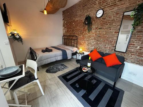 una camera da letto con divano, letto e muro di mattoni di Hermoso apartamento estudio en el centro de Madrid a Madrid