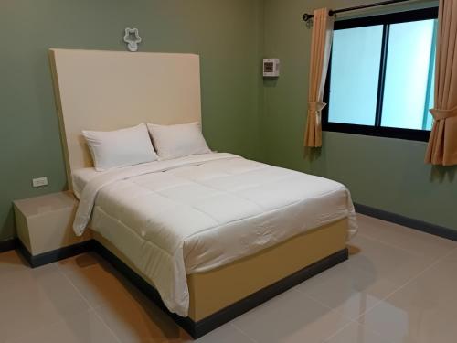 a bedroom with a large bed with white sheets and a window at Fairy Resort - แฟรี่รีสอร์ท in Ban Tha Thon