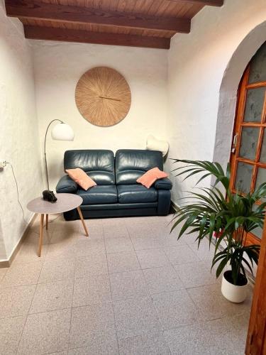 a living room with a black leather couch and a table at El Paraíso Agaete Valle in Agaete