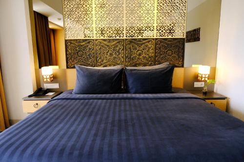 a bedroom with a blue bed with blue pillows at Horison Ultima Seminyak Bali - CHSE Certified in Seminyak