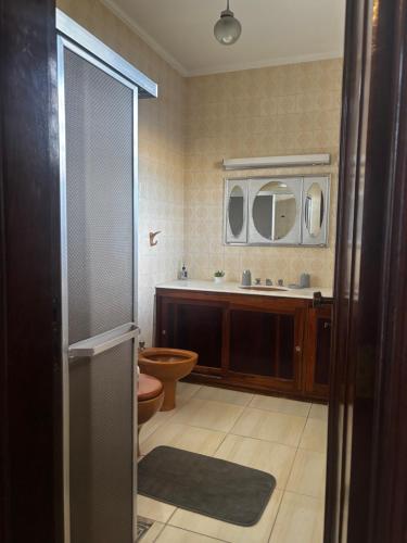 a bathroom with a toilet and a sink and a mirror at ALAMEDA iNN in Poços de Caldas