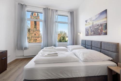 a bedroom with a large white bed with two windows at Altstadt Residenz in Lübeck