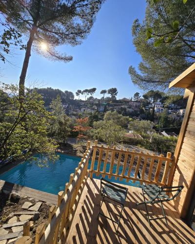 un banc en bois assis sur une terrasse à côté d'une piscine dans l'établissement La Cabane Aixoise Piscine & Jacuzzi, à Aix-en-Provence