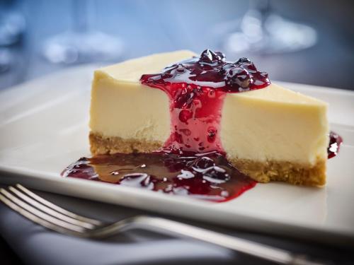 a piece of cheesecake on a plate with a fork at Mercure Thurrock Stifford Hall in Grays Thurrock