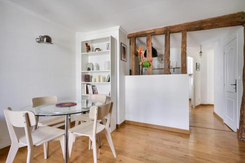 une salle à manger avec une table en verre et des chaises blanches dans l'établissement Stunning 1BR Flat with balcony near metro station, à Paris
