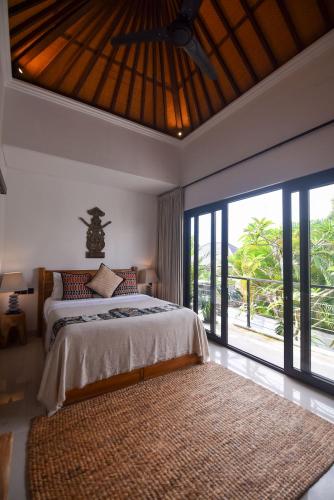 a bedroom with a bed and a large window at Sister Suites in Seminyak