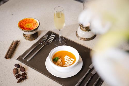 a table with a bowl of soup and a glass of champagne at Indochine Grand Lan Ha Bay in Ha Long