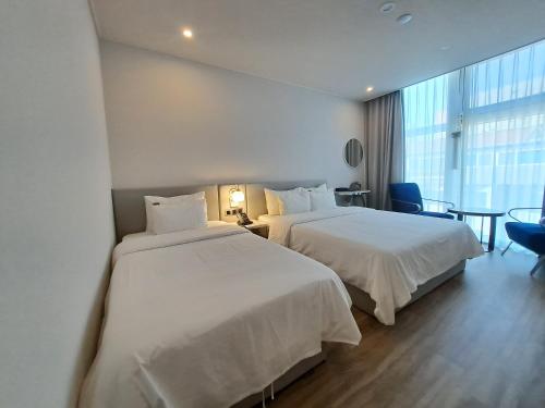 a hotel room with two beds and a window at Ocean The Point Hotel Busan in Busan