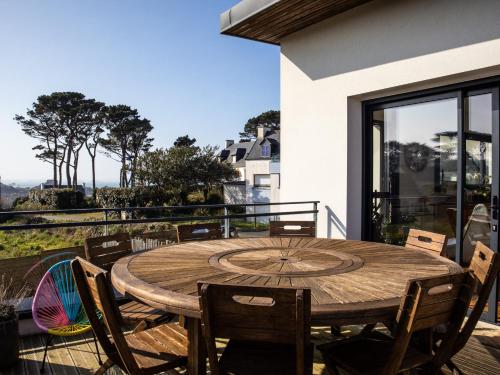 une table et des chaises en bois assises sur un balcon dans l'établissement Villa lumineuse vue mer 150m plage, à Plougasnou
