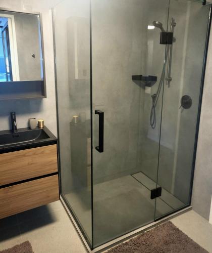 a shower with a glass door next to a sink at Epsom Escape Stylish Apartment in Auckland
