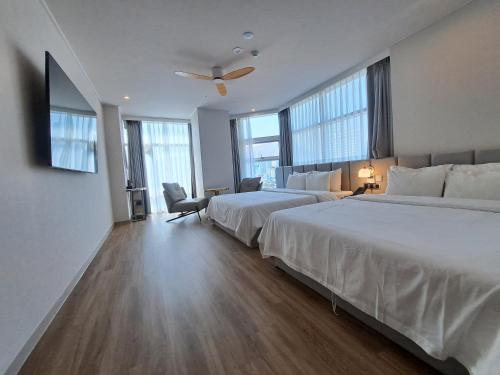 a hotel room with two beds and a ceiling fan at Ocean The Point Hotel Busan in Busan