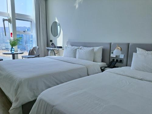 two white beds in a hotel room with a window at Ocean The Point Hotel Busan in Busan