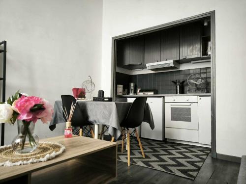 une cuisine avec une table et quelques armoires noires dans l'établissement Appartement dans le cœur historique d'Avignon, à Avignon